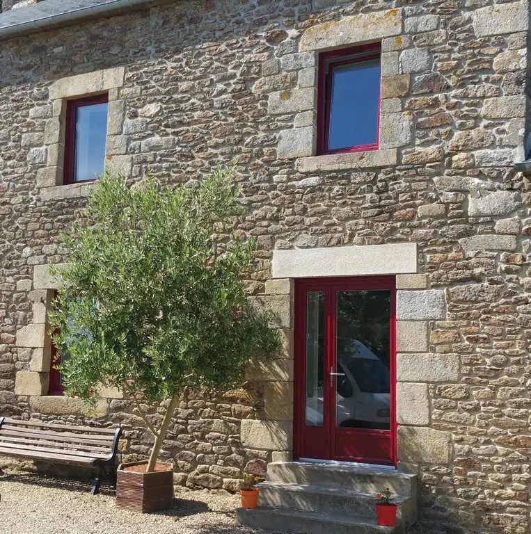 Maison en pierre aux fenêtres et à la porte rouges